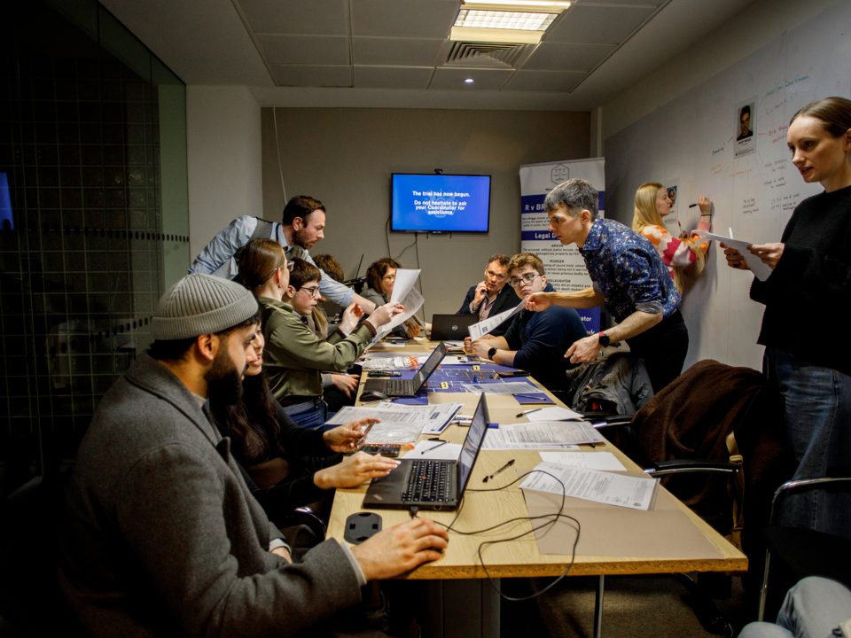 Jurors discuss evidence around a table with live performers.